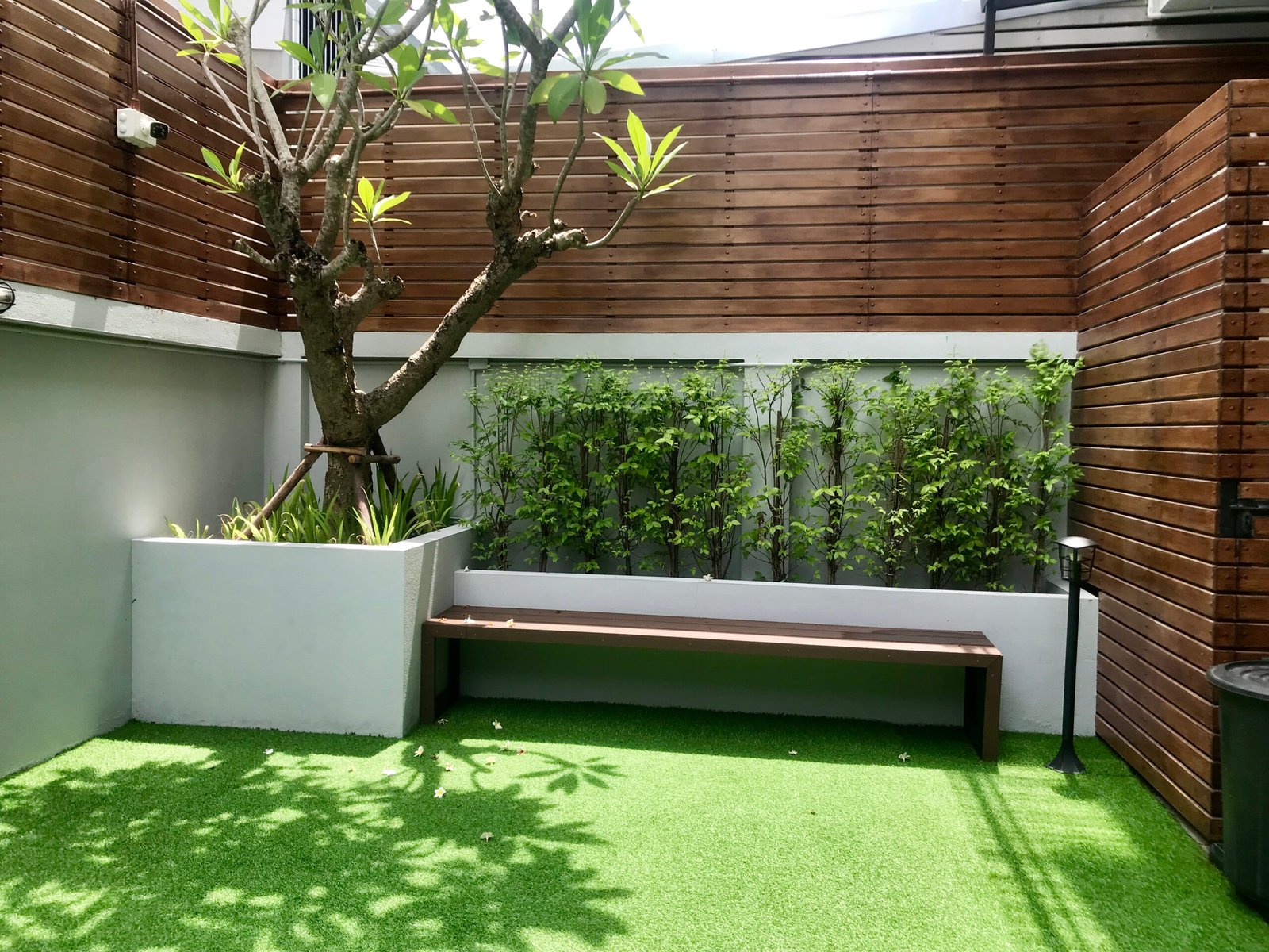 Modern garden design with cladding, artificial grass and raised planter