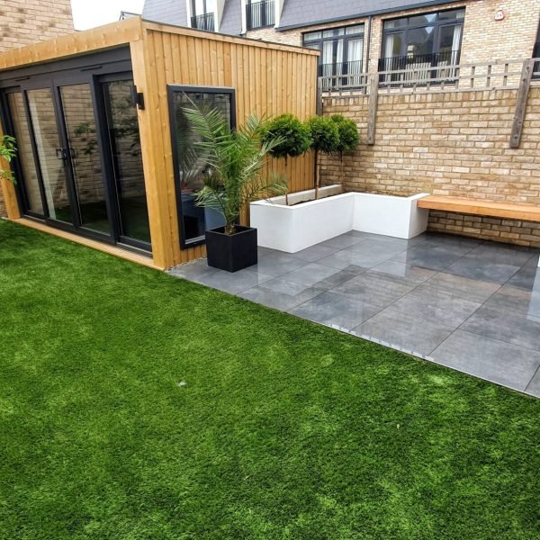 Modern patio and seating area with garden room and artificial grass
