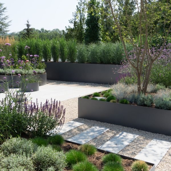 Contemporary garden design with raised planters and paved areas